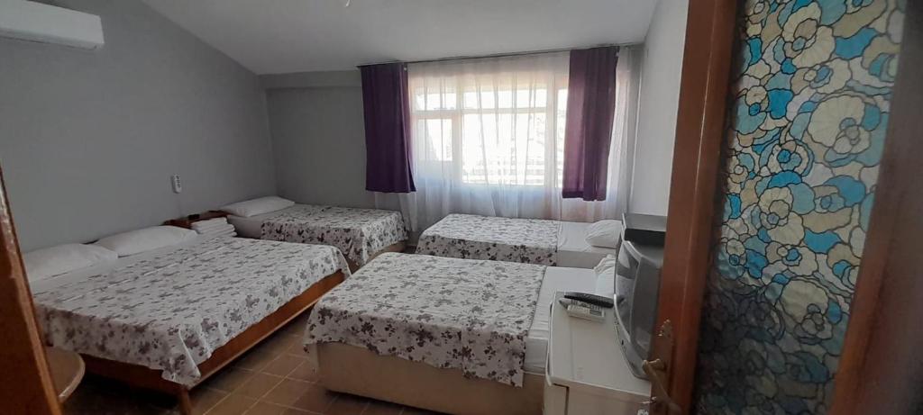 um quarto com três camas e uma janela em Set Arat Motel & Pansiyon em Akçay