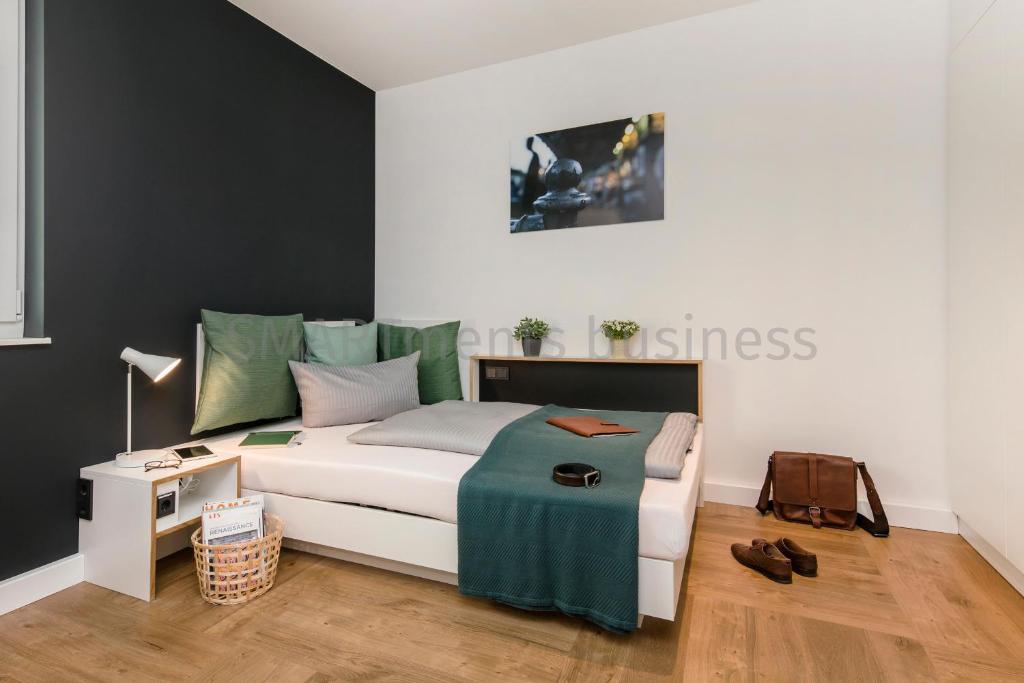 a bedroom with a bed and a table with a night stand at SMARTments business Berlin Prenzlauer Berg in Berlin