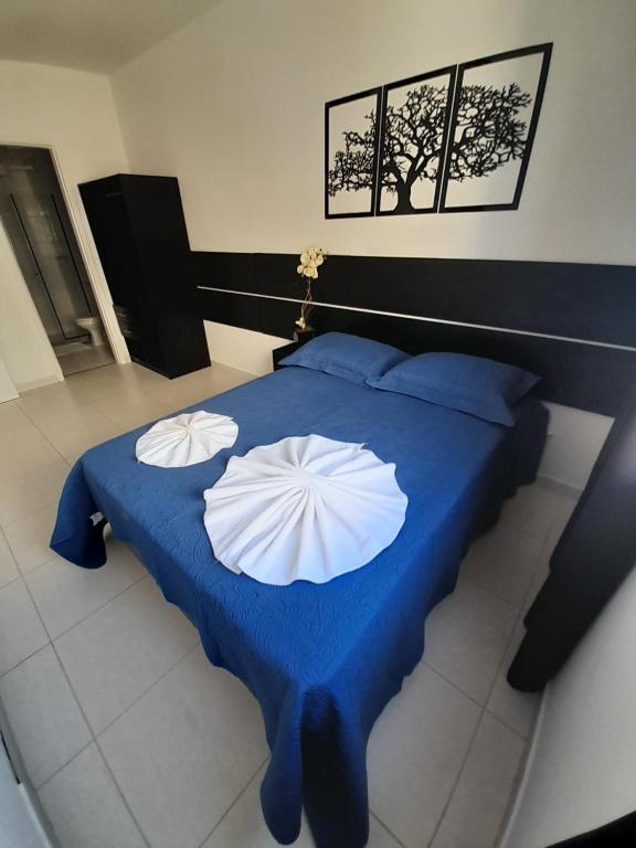 - un lit bleu avec 2 oreillers blancs dans l'établissement Itaguaí Flats, à Itaguaí