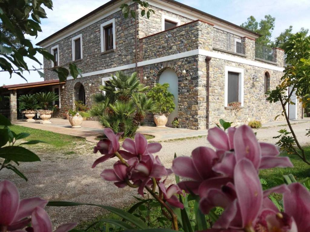 uma casa de pedra com flores cor-de-rosa à frente. em Anna dei Sapori em Castelnuovo Cilento