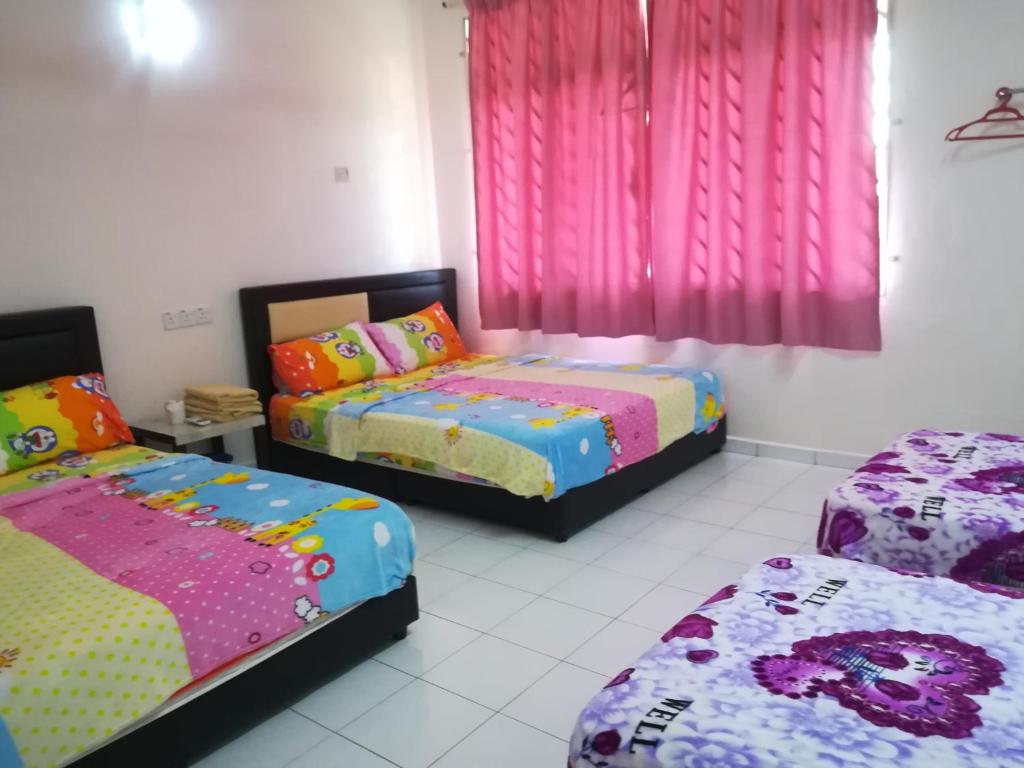 a bedroom with two beds and pink curtains at 30 Guest House in Malacca