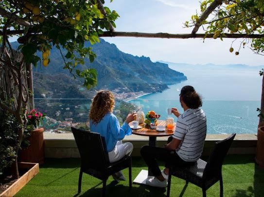 two women sitting at a table with a view of the ocean at Da Salvatore B&B in Ravello