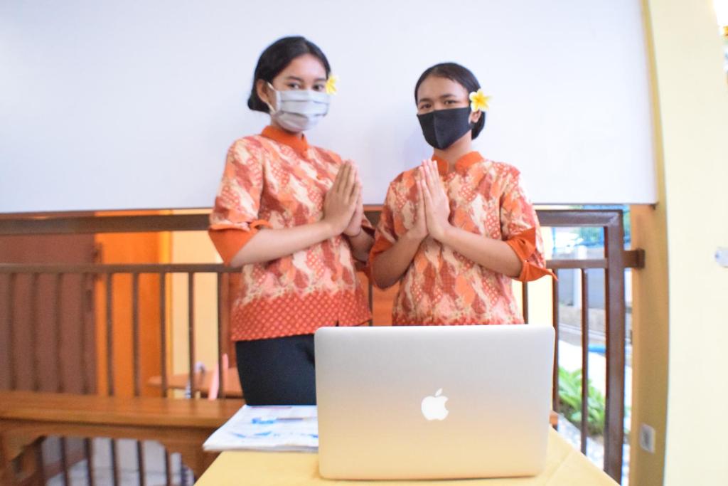 two girls wearing face masks standing in front of a laptop at KJ Inn Homestay Senggigi in Senggigi 