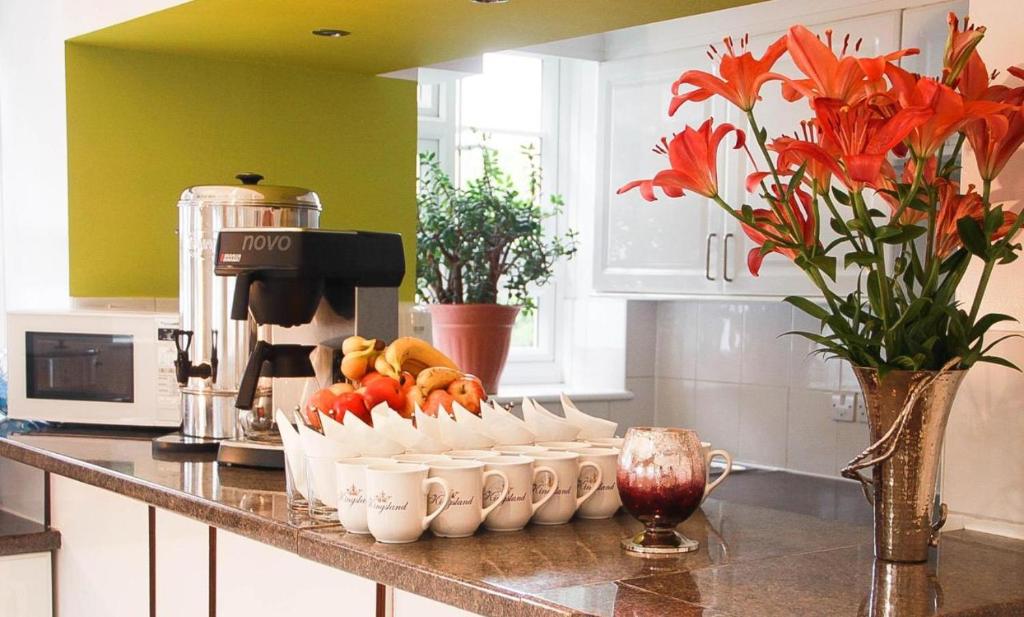 a kitchen counter with a bunch of bowls of fruit at Kingsland Hotel in Harrow