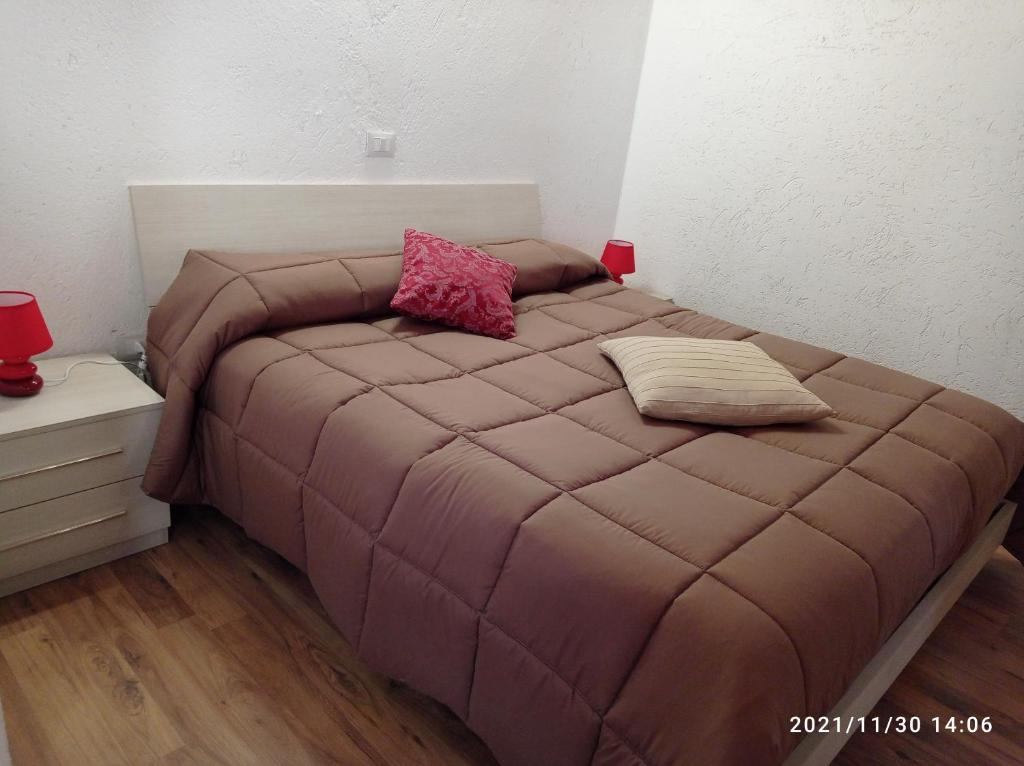 1 cama con edredón marrón y 2 almohadas en Casa vacanze Casa di Corte, en Adrara San Rocco