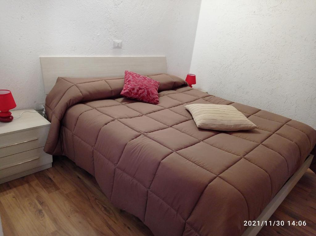 a bed with a brown comforter and two pillows on it at Casa vacanze Casa di Corte in Adrara San Rocco