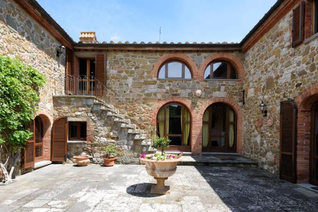 ein Steingebäude mit einem Innenhof mit einer Vase in der Unterkunft Villa di Leonardo in Sinalunga