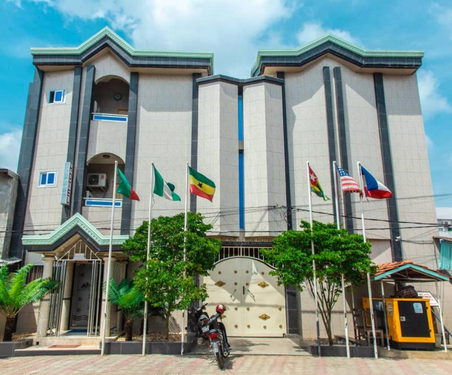 un homme sur une moto devant un bâtiment avec drapeaux dans l'établissement Bénin Berge hotel, à Cotonou