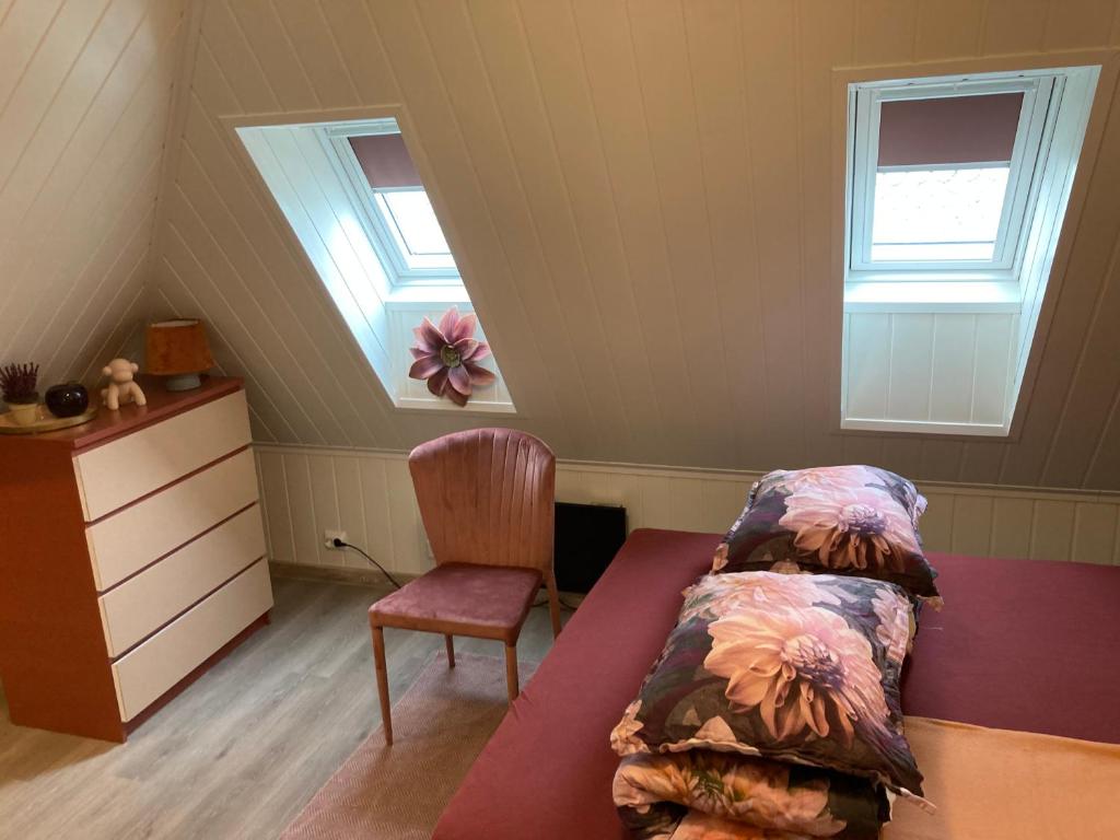 a attic bedroom with a bed and a chair at Downtown Historical House with Renovated apartments in Ålesund