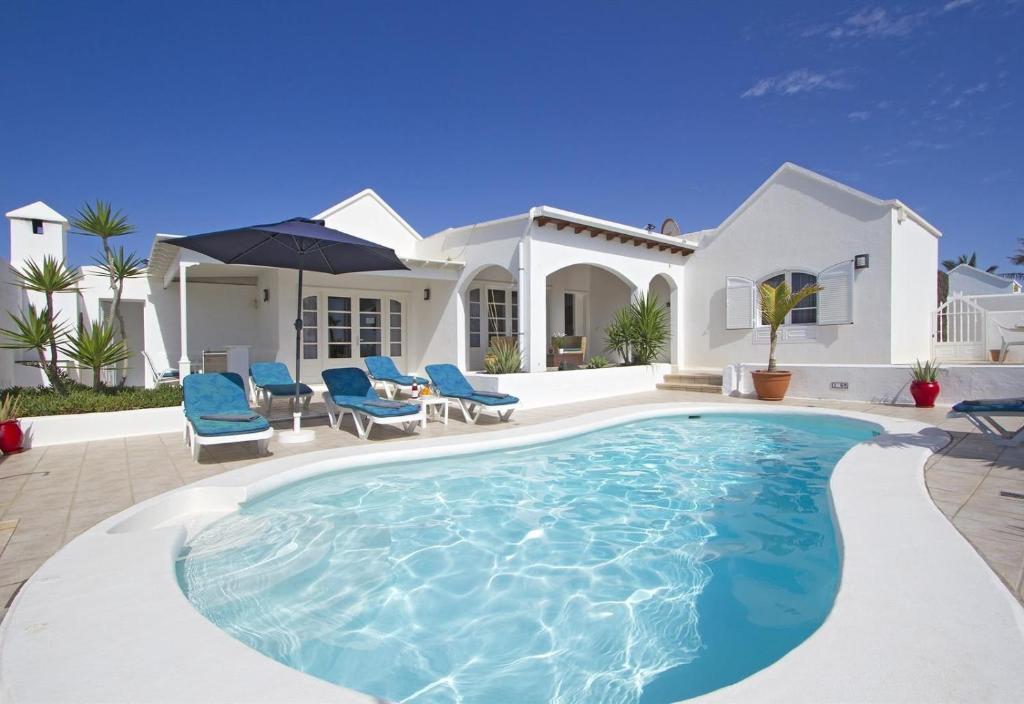 a swimming pool in front of a house at Villa de Carrida in Puerto del Carmen