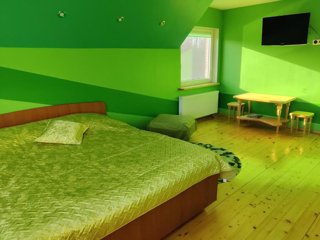 a green bedroom with a bed and a table at Stay at Svaja in Plungė