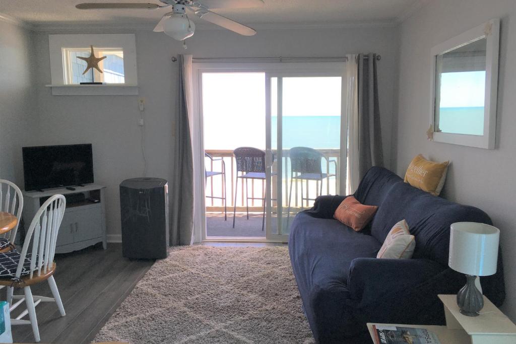 ein Wohnzimmer mit einem blauen Sofa und einem Balkon in der Unterkunft Totally Topsail! in North Topsail Beach