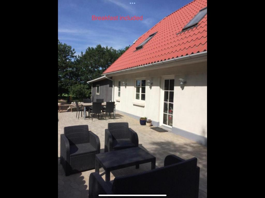 een patio met stoelen en tafels en een rood dak bij Billund Holiday - Assengaard B & B in Give