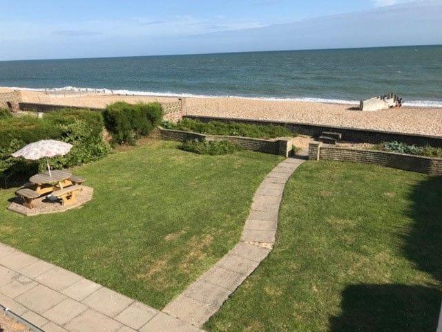 an aerial view of a lawn with an umbrella and the beach at 11 Shorecroft, Aldwick in Bognor Regis