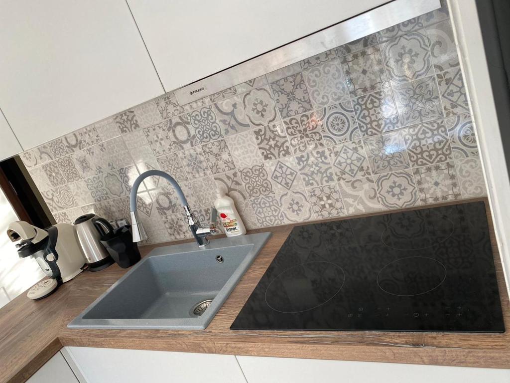 a kitchen with a sink and a tile wall at Appartement in Kallikratia in Nea Kallikrateia