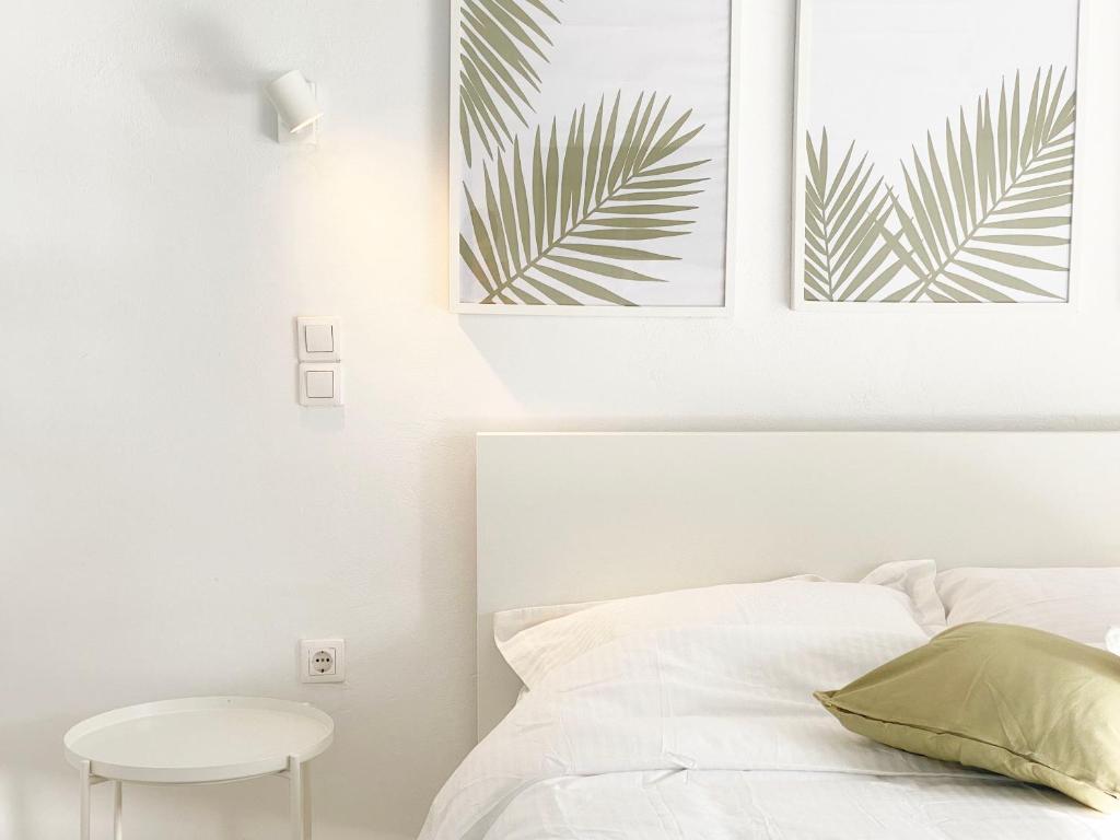 a white bedroom with a bed and a table at Palm Suite Green in Porto Heli