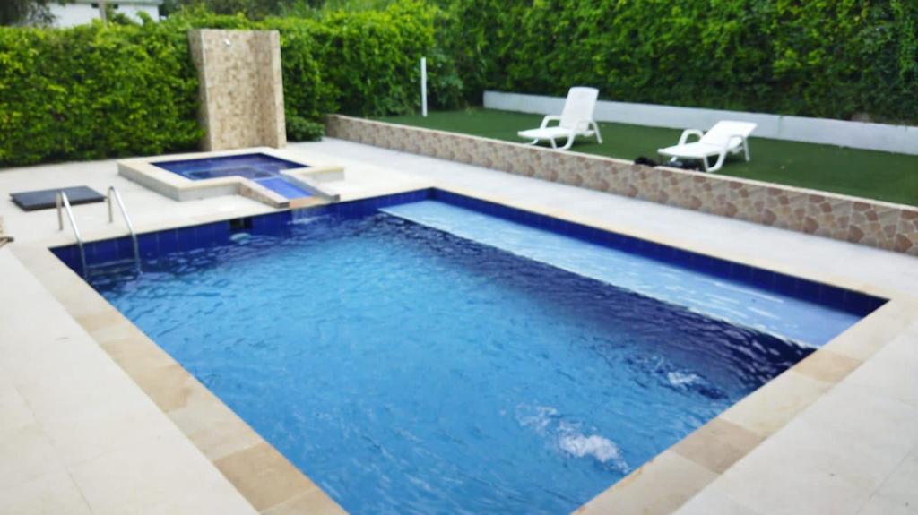 a swimming pool with two chairs in a yard at Casa campestre in Ricaurte