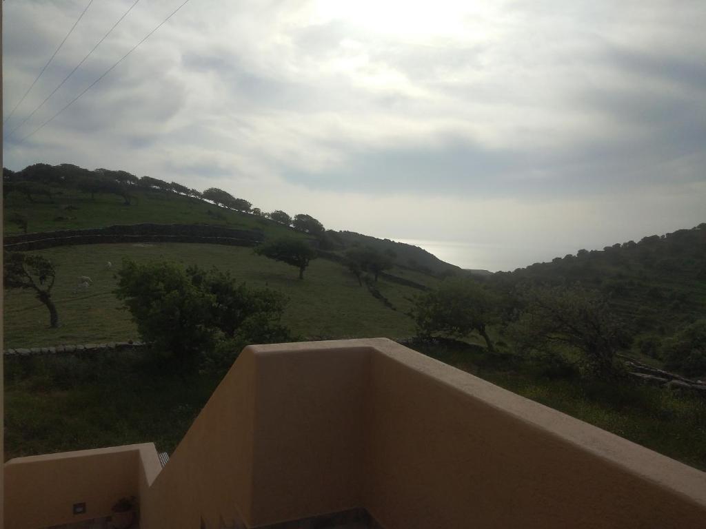 un balcón con vistas a una colina verde. en Αγ Νικόλαος Karthaia en Elliniká
