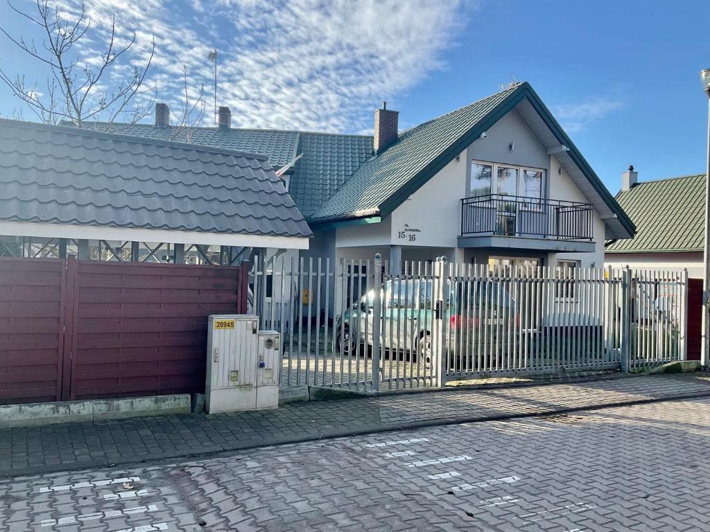 a white house with a fence and a car at Apartamenty u Lucyny i Lecha in Łukęcin