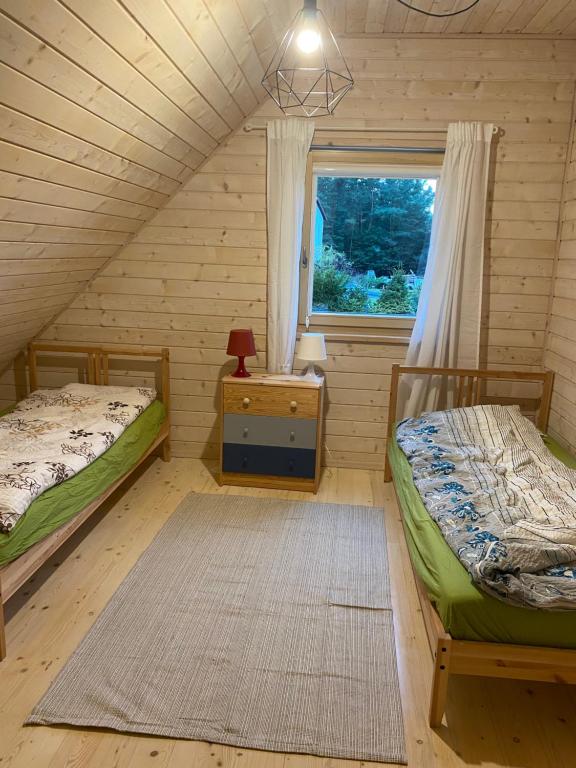 OdargowoにあるDębki na spokojnieのベッドルーム1室(ベッド2台付)、窓が備わります。