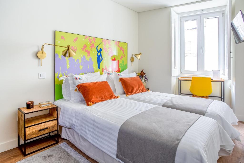 una camera da letto con un grande letto bianco con cuscini arancioni di Bairro Alto Music Guest House a Lisbona