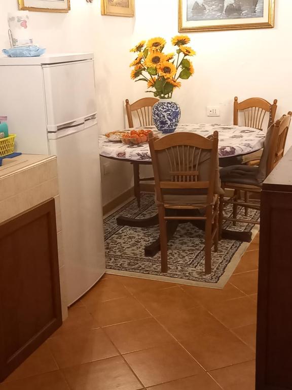 una cucina con tavolo, frigorifero, tavolo e sedie di Appartamento stile toscano in Fauglia a Fauglia
