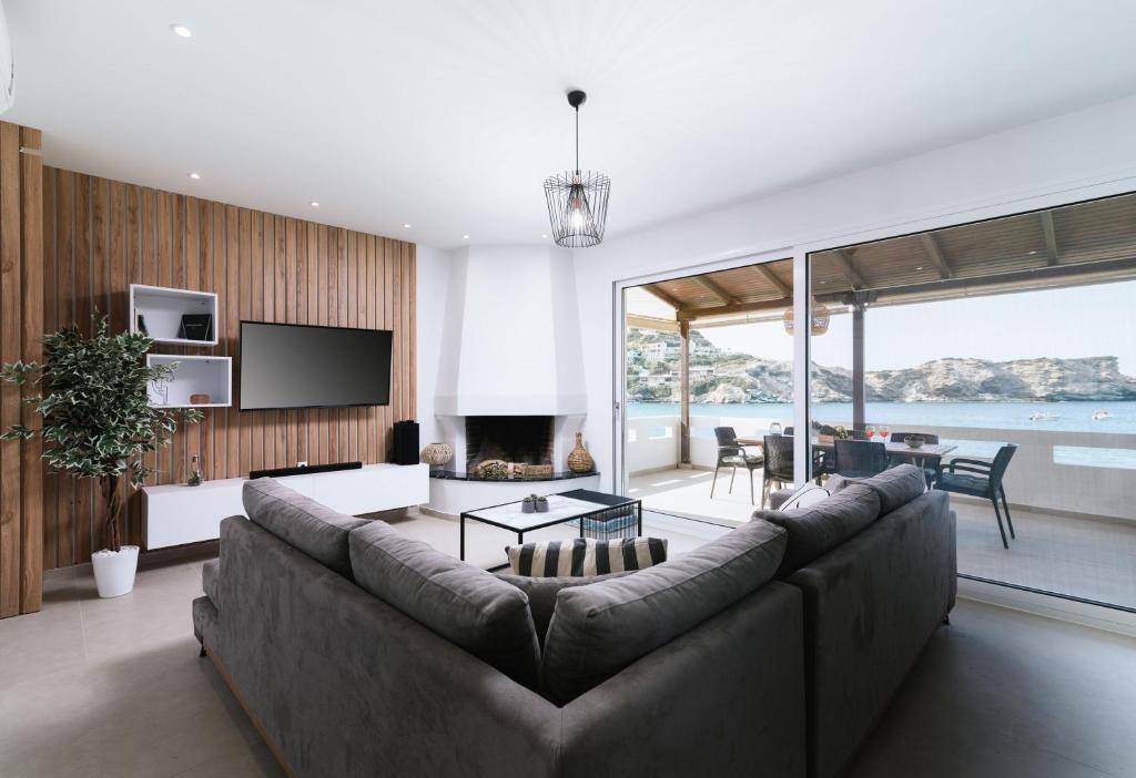 sala de estar con sofá grande y TV en Beach front apartment with swimming pool, en Ligaria
