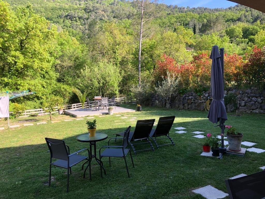 une table et des chaises dans l'herbe avec un parasol dans l'établissement Studio calme et agréable avec acces jardin partage, à Le Bar-sur-Loup