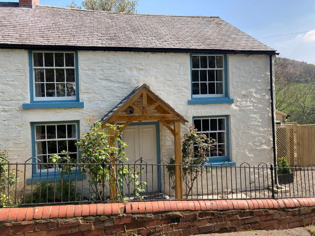 uma casa branca com janelas azuis e uma cerca em Avondale em Llangollen