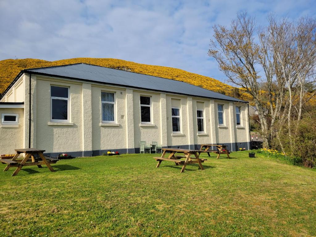un edificio con dos mesas de picnic delante de él en Helmsdale Lodge Hostel - all rooms en-suite en Helmsdale