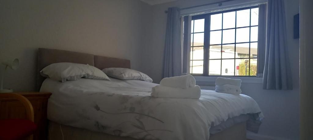 a bedroom with a bed with white sheets and a window at CORSBIE VILLA GUEST HOUSE in Newton Stewart