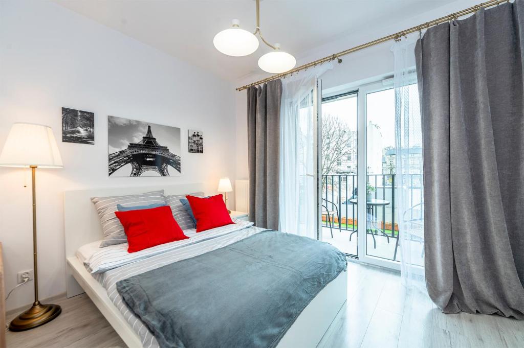 a bedroom with a bed with red pillows and a large window at Luxury in City -3- Studio Bright & Secure Free Parking in Łódź