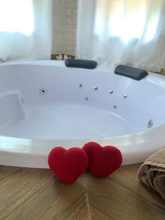 a white tub with two red hearts on the floor at Chale Villa do Valle in Monte Verde