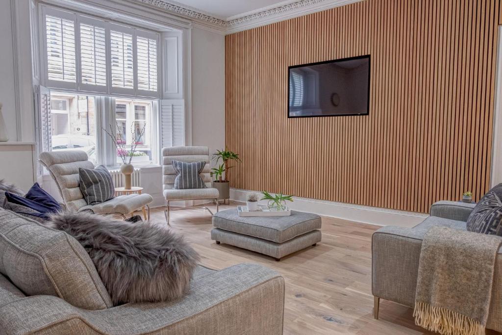 a living room with a couch and a tv on a wall at Andrean House, St Andrews in St Andrews