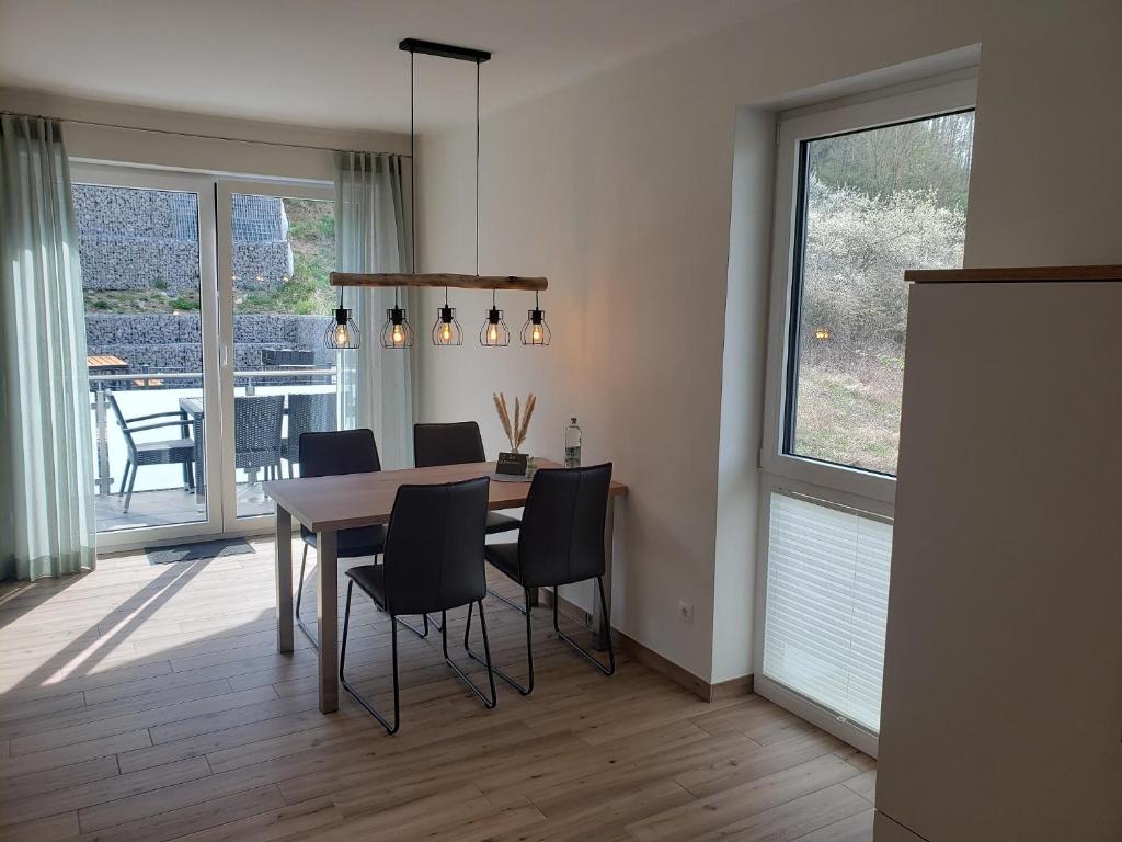 a dining room with a table and black chairs at Ferienwohnungen am Aeppelsberg in Volkesfeld