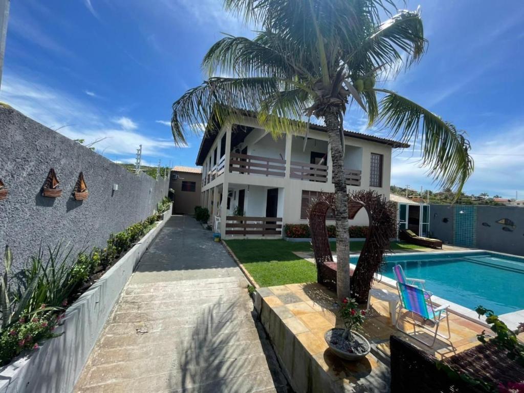 a house with a palm tree and a swimming pool at casa brisa do mar in Aquiraz