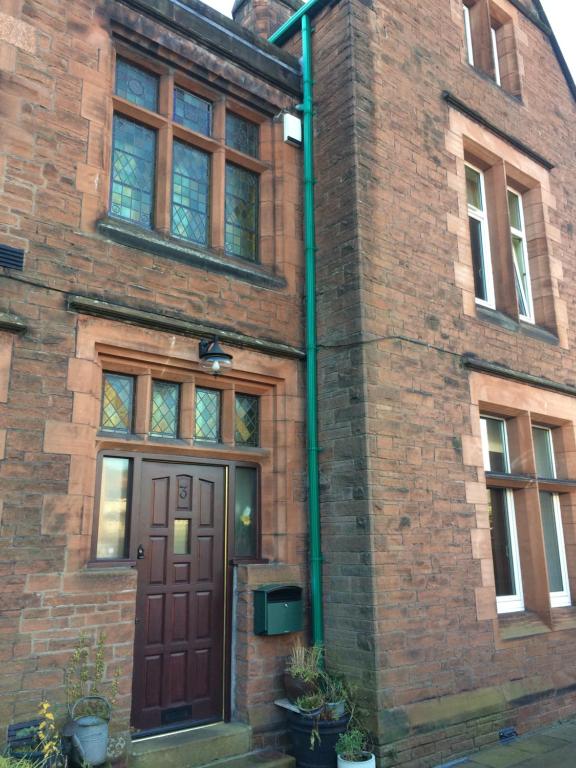 a brick building with a brown door and windows at Stylish Apartment in Stone-Built Former Rectory in Penrith