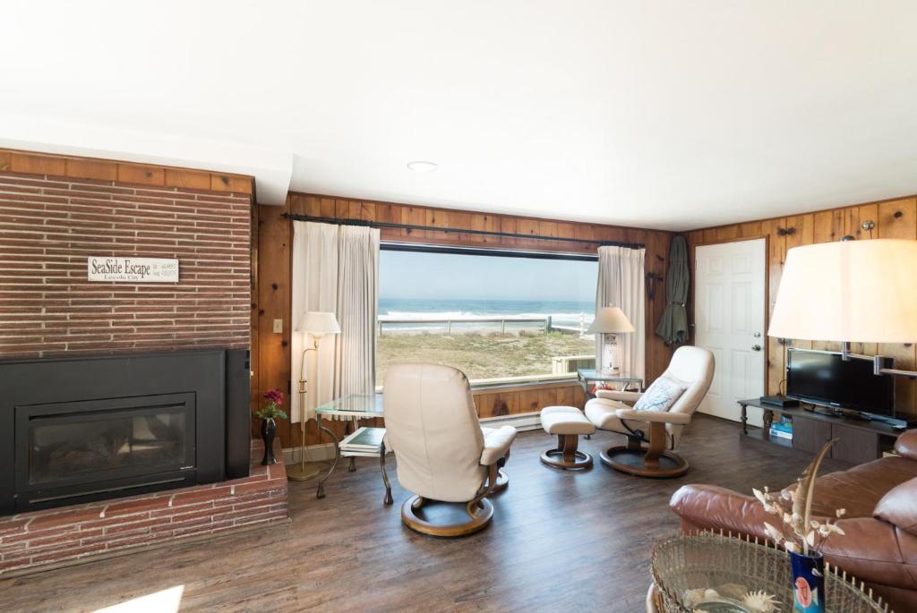 een woonkamer met een open haard en een bank en stoelen bij Seaside Escape in Lincoln City