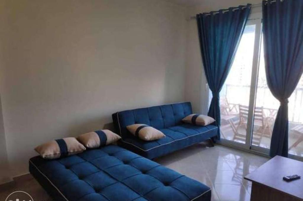 a blue couch in a living room with a window at شقه للايجار بورتو السخنه ألعاب مائية فرش مميز فندقي مكيفه in Ain Sokhna