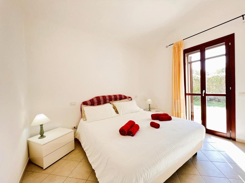 a bedroom with a white bed with red pillows on it at Sa Perda 20 - FREE WIFI - 500mt from the beach in Costa Rei