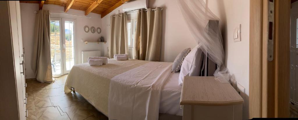 a bedroom with a large white bed and a window at Julia house in Pilaroú
