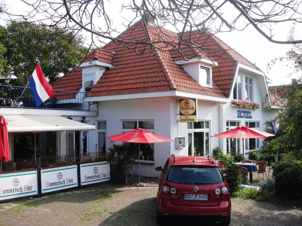 um carro vermelho estacionado em frente a um edifício em De Zilvermeeuw em Westenschouwen