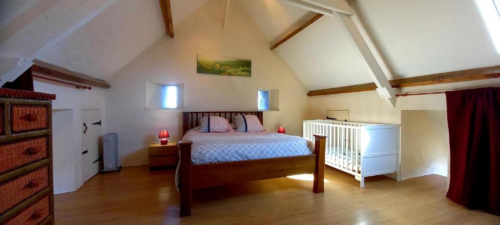 a bedroom with a bed and a crib in a attic at L' Anpeg, gîte dans le Cotentin jusqu'à 8 personnes in Besneville