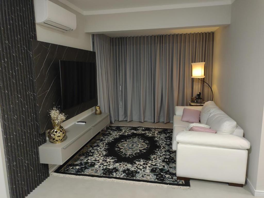 a living room with a white couch and a tv at AP novo, bairro nobre, ótima localização, Vale dos Vinhedos, Fenavinho in Bento Gonçalves