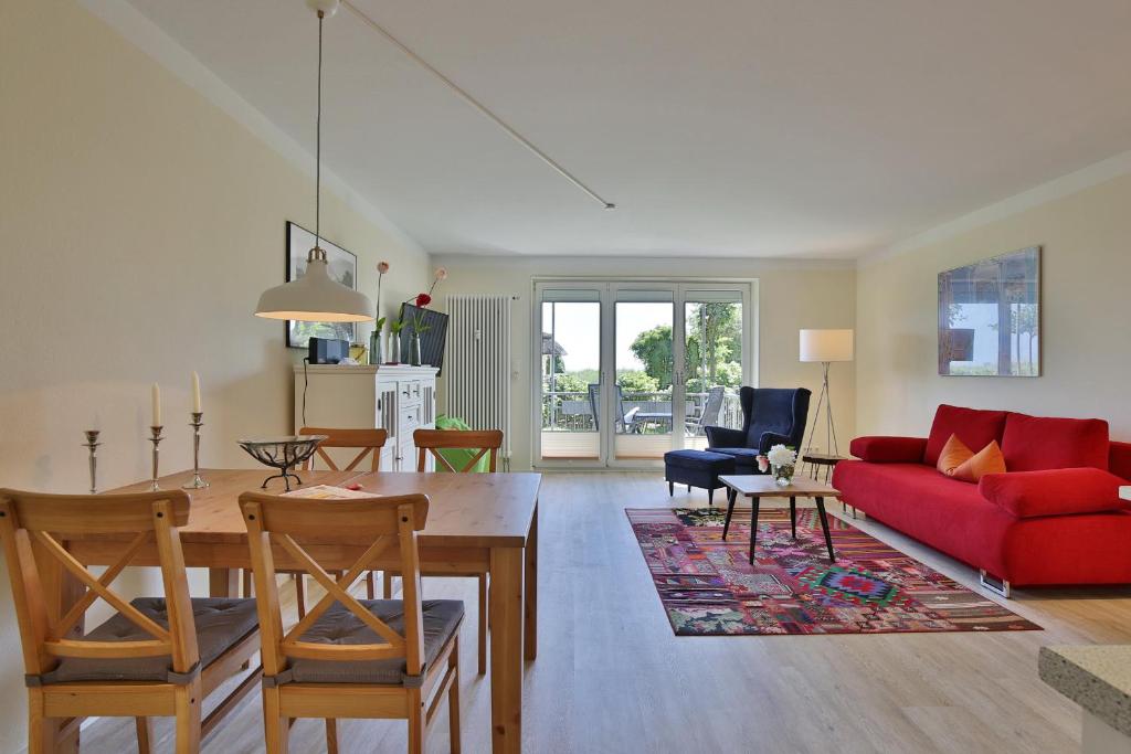 een woonkamer met een rode bank en een tafel bij Strandduene Stranddüne Appartement 3 in Haffkrug