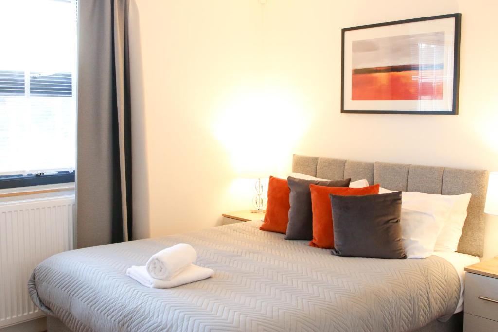 sypialnia z łóżkiem z pomarańczowymi poduszkami i oknem w obiekcie Exclusive Ensuite Double Room w Londynie