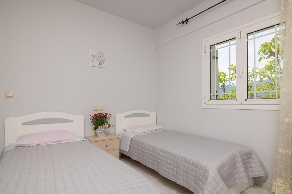 two beds in a white room with two windows at En Elladi Apartment in Alikanas