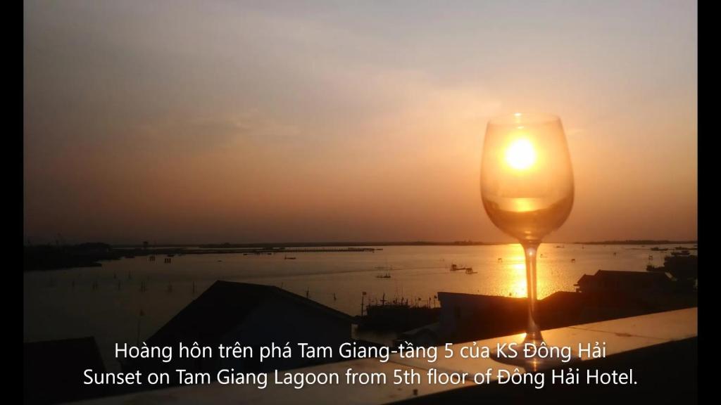 a candle in front of the sun with the sunset at Dong Hai Hotel in Phú Vang