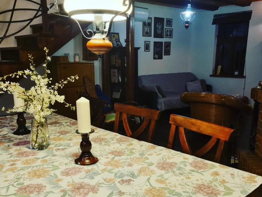 una mesa de comedor con una vela y un jarrón de flores en Szydlukówka, en Janów Podlaski