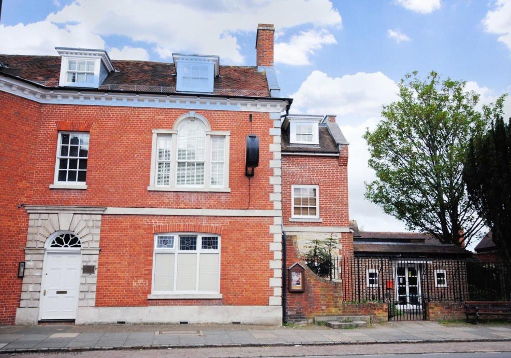 a red brick house with a white door at 4 The Clockhouse , Midhurst in Midhurst